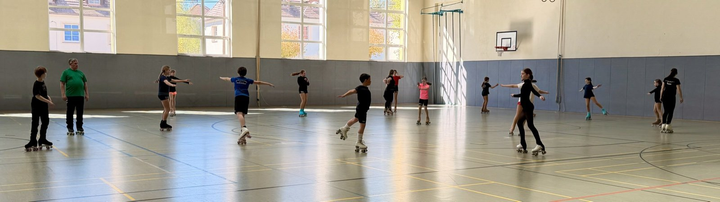 Sportlerinnen und Sportler üben ein Element gemeinsam in der Turnhalle