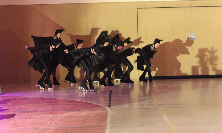 Formation in schwarzen Umhängen mit Schattenwurf an der Hallenwand